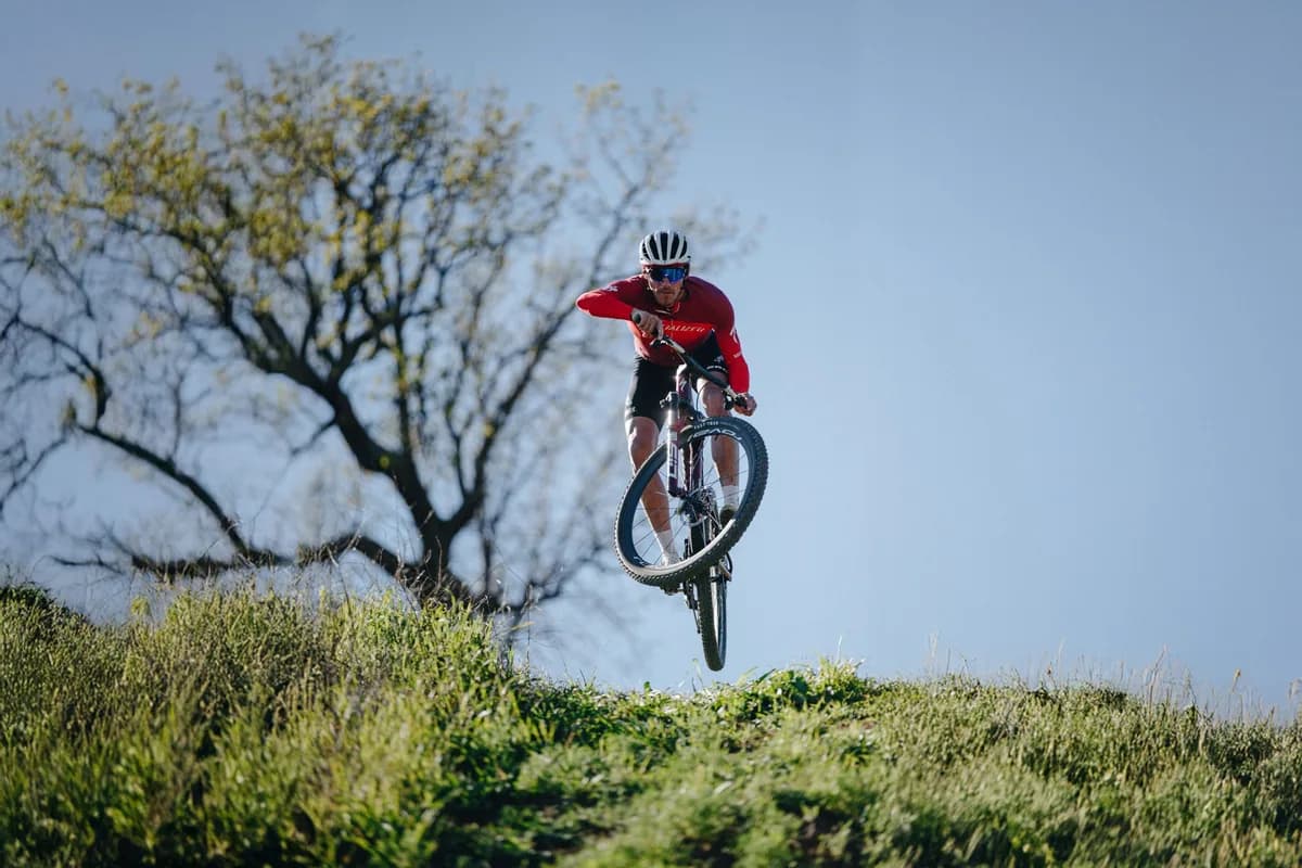 Cross-country rider jumping and turning the bars in the air aboard new Specialized Epic 9.
